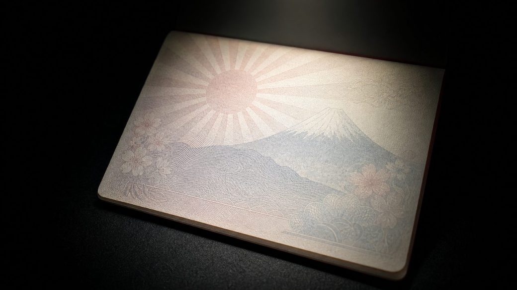 A single Japanese passport visa page with a faint Mount Fuji and rising-sun motif under a dramatic spotlight, dark uncluttered background, high contrast, no readable text